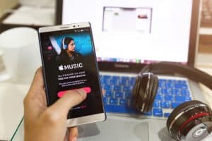 一個男人手拿著在 Android 上顯示的 Apple 音樂應用程序的屏幕截圖。  Apple Music 是基於 iTunes 的全新音樂流媒體服務，現已登陸 Android。