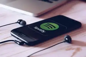 智能手機躺在桌子上，屏幕上運行著 Spotify 音樂應用程序。 社交媒體概念。