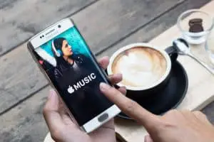 一個男人手拿著蘋果音樂應用程序的屏幕截圖，顯示在三星 Galaxy s6 邊緣。  Apple Music 是 Android 上的測試版。